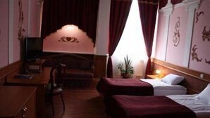 A hotel room with a bed, a desk, a chair, and a window with curtains. - Hotel Volter (Lviv)