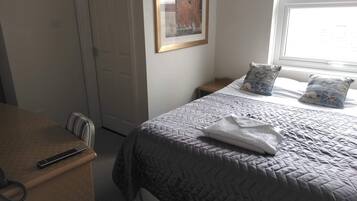 Une chambre à coucher avec un lit, des tables de chevet, un bureau et un tableau encadré au mur.