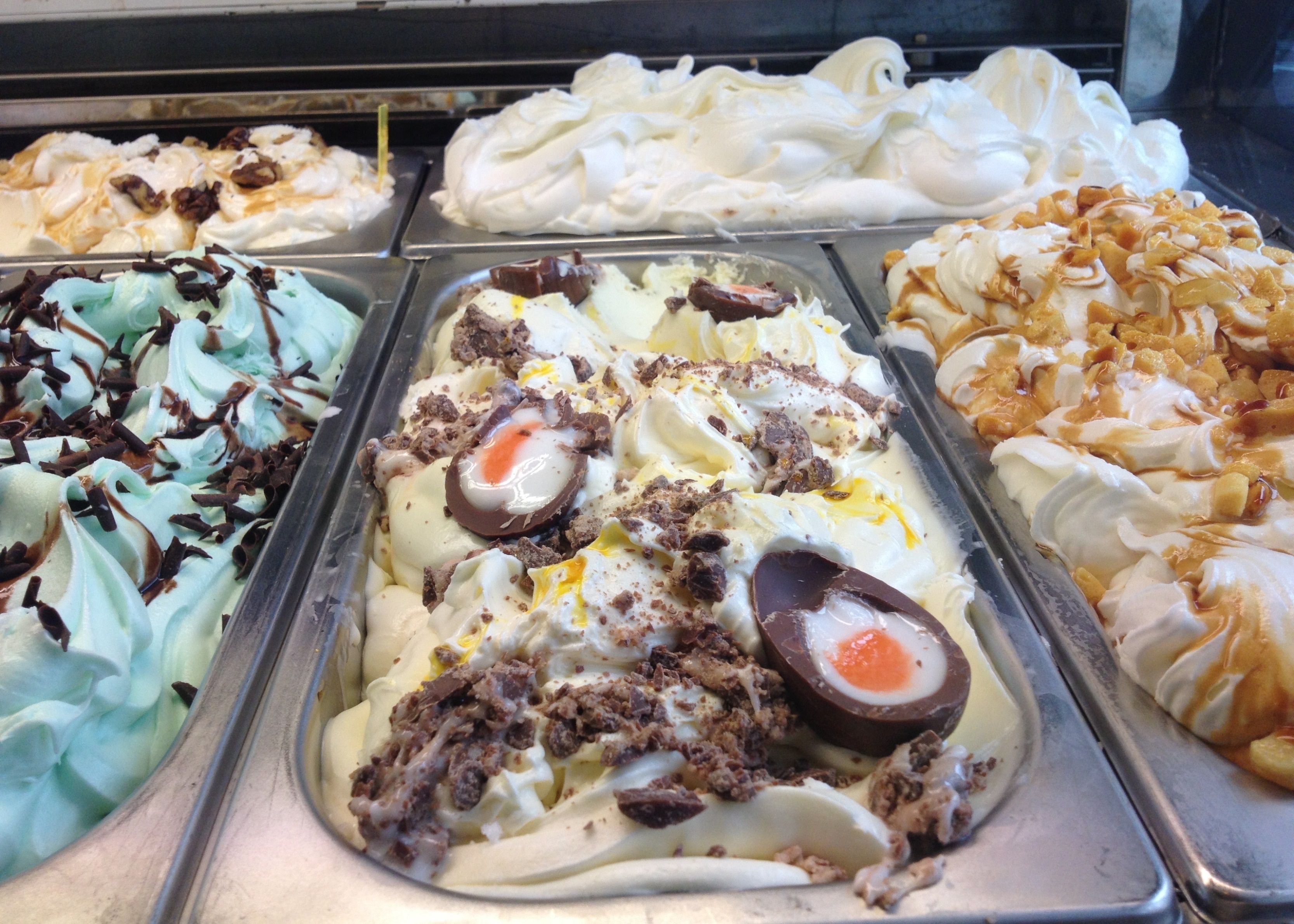 A dessert display with various ice cream flavors and toppings.