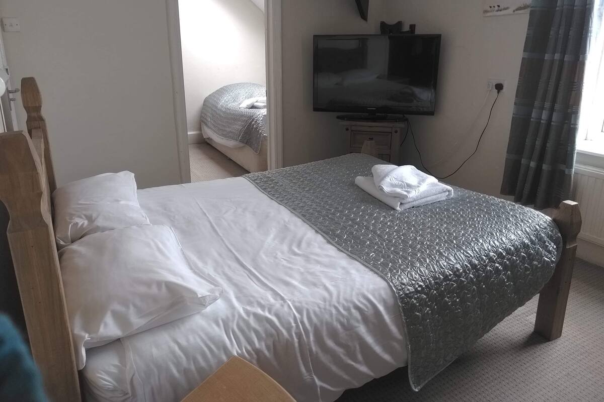 A hotel room with a bed, a television, and a window with curtains.