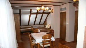 Een eetruimte met een houten tafel en stoelen, een kroonluchter en een raam met uitzicht.