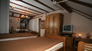 Een slaapkamer met twee bedden, houten meubels, een televisietoestel en een lamp.