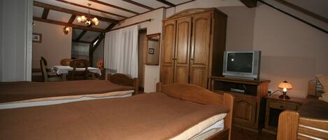 A bedroom with two beds, wooden furniture, a television, and a lamp.