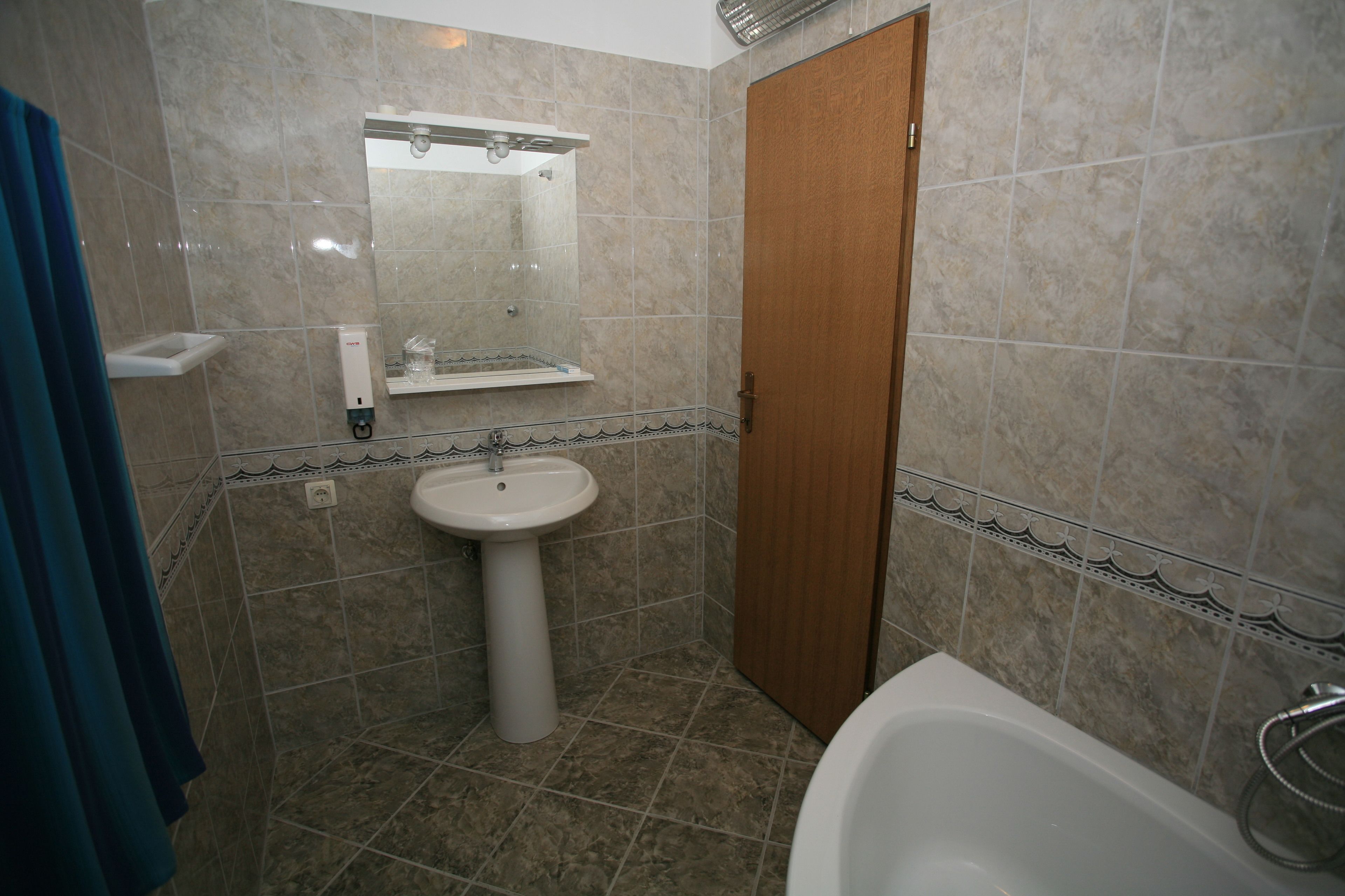 A bathroom with a sink, mirror, and bathtub.