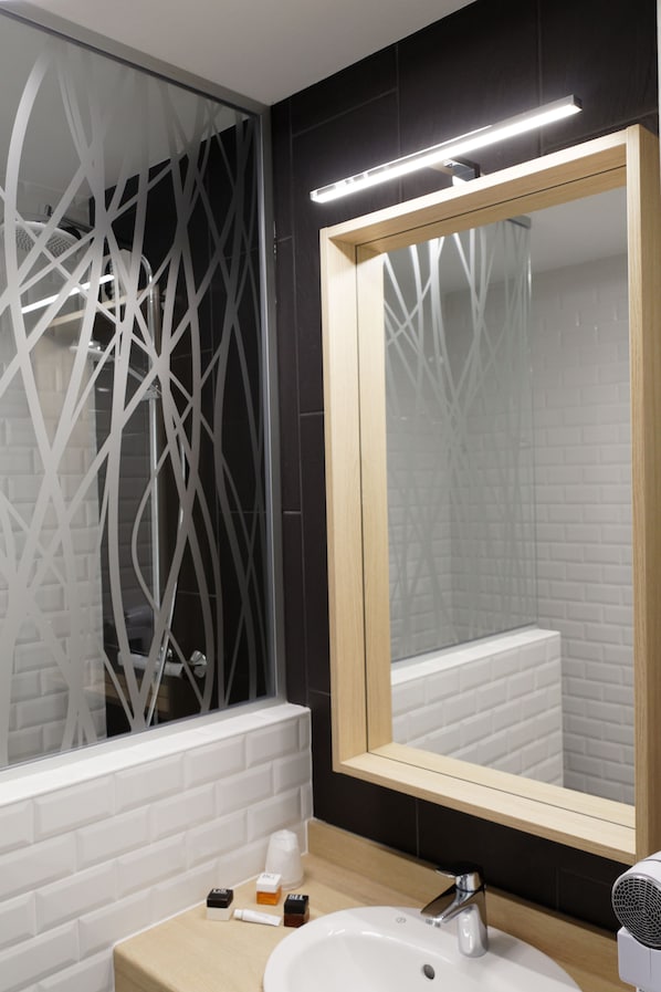 A modern bathroom with a white sink, a mirror, and a decorative glass partition. - Hotel Bastide (Onet-le-Chateau)