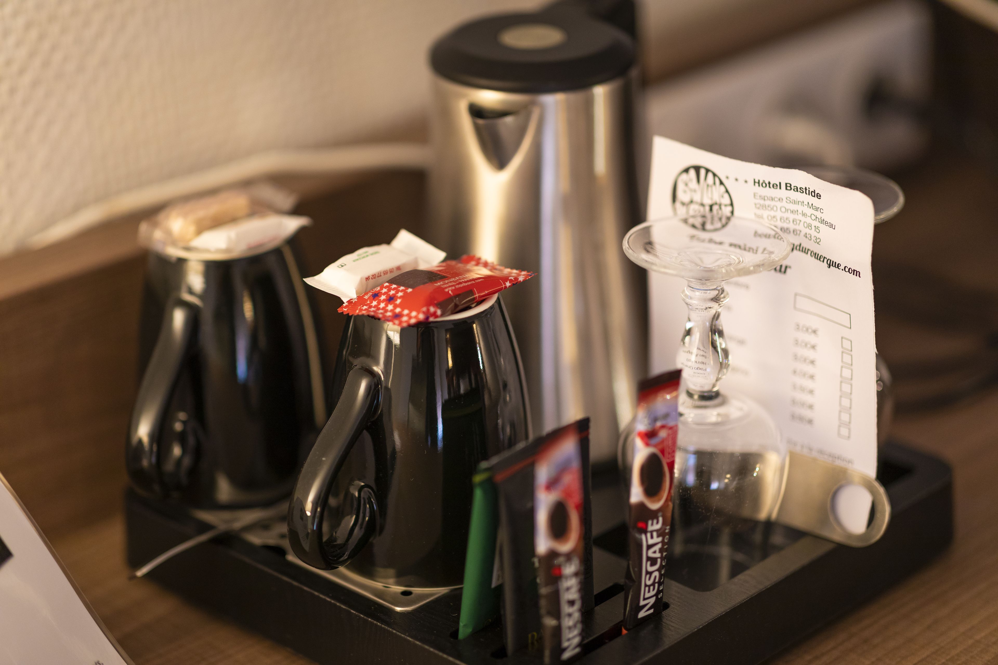 A hotel room with a coffee maker, a kettle, and a Nespresso machine on a tray.