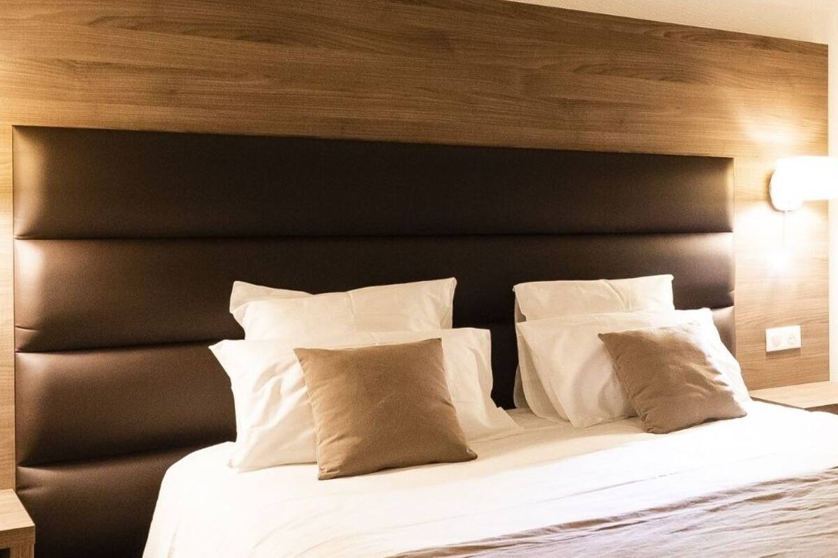 A hotel room with a large bed, two bedside tables, and a wooden headboard.