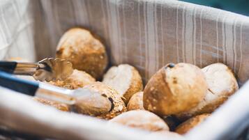 A basket of bread rolls with a tongs resting on top.