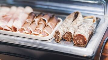 Una vitrina con diversos tipos de embutidos curados, como salchichas enrolladas y salami en rodajas.