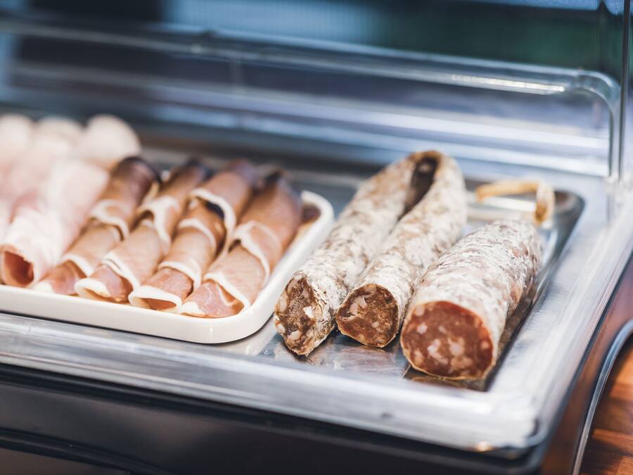 Una vitrina con diversos tipos de embutidos curados, como salchichas enrolladas y salami en rodajas.