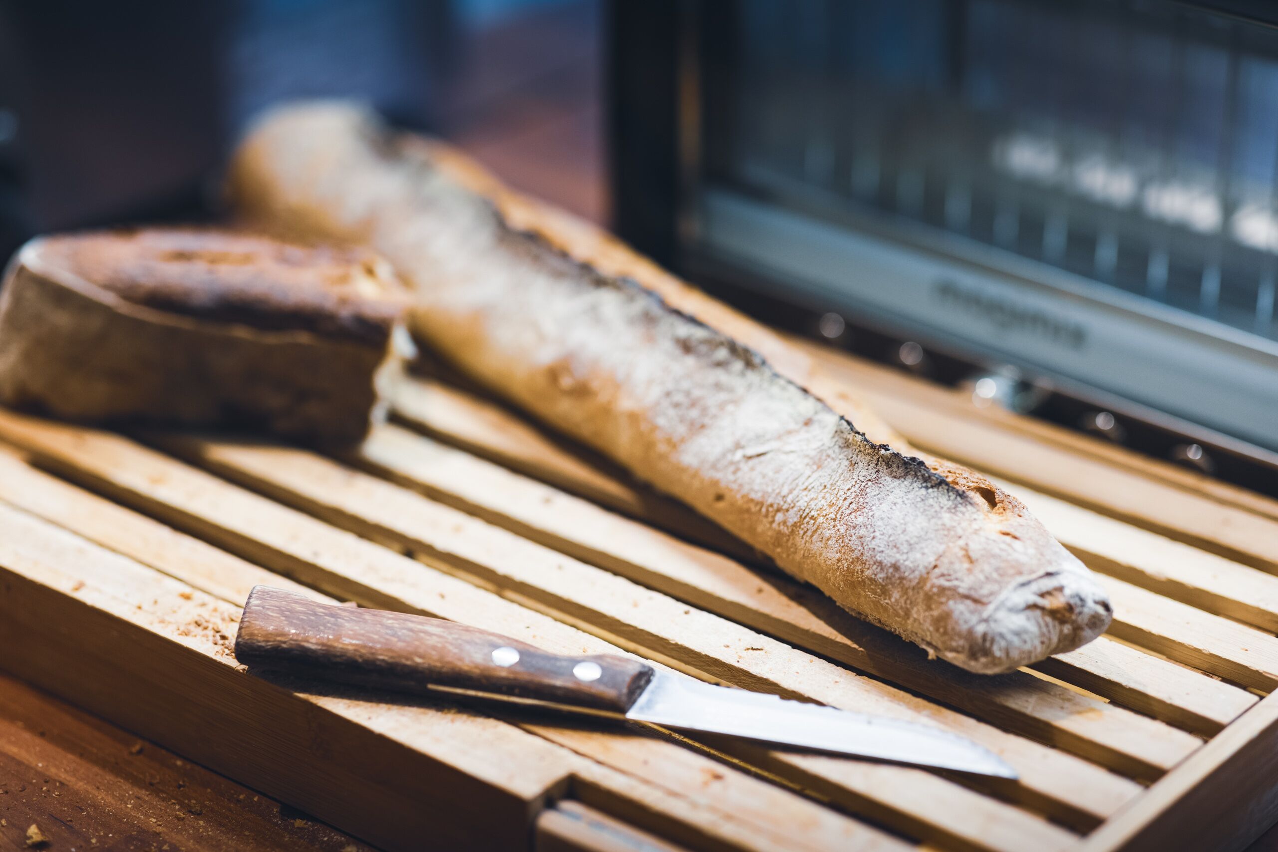 En baguette på en träskärbräda, med en kniv bredvid.