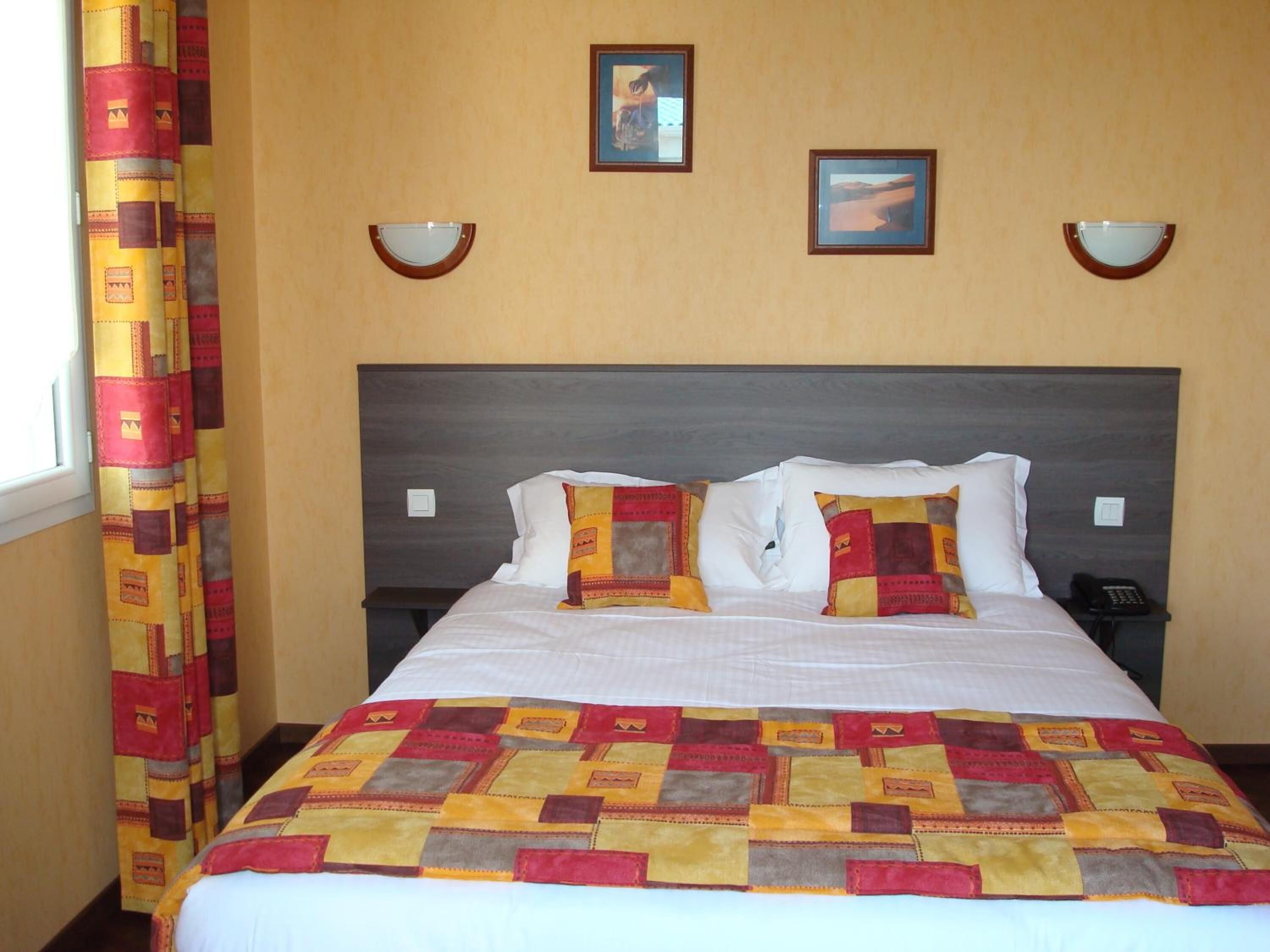 Een hotelkamer met een groot bed, twee bedlampen en een raam met gordijnen.