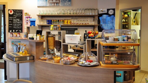 Una barra de desayuno con diversos alimentos, una máquina de café y cristalería en estantes.
