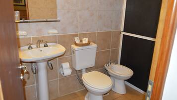 A bathroom with a sink, toilet, and bidet.