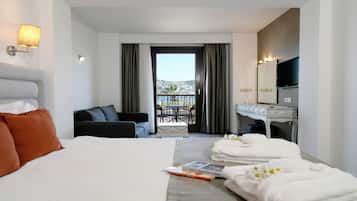 Ett hotellrum med en säng, en soffa, ett matbord med stolar, ett badrum med en spegel och utsikt över omgivningarna.