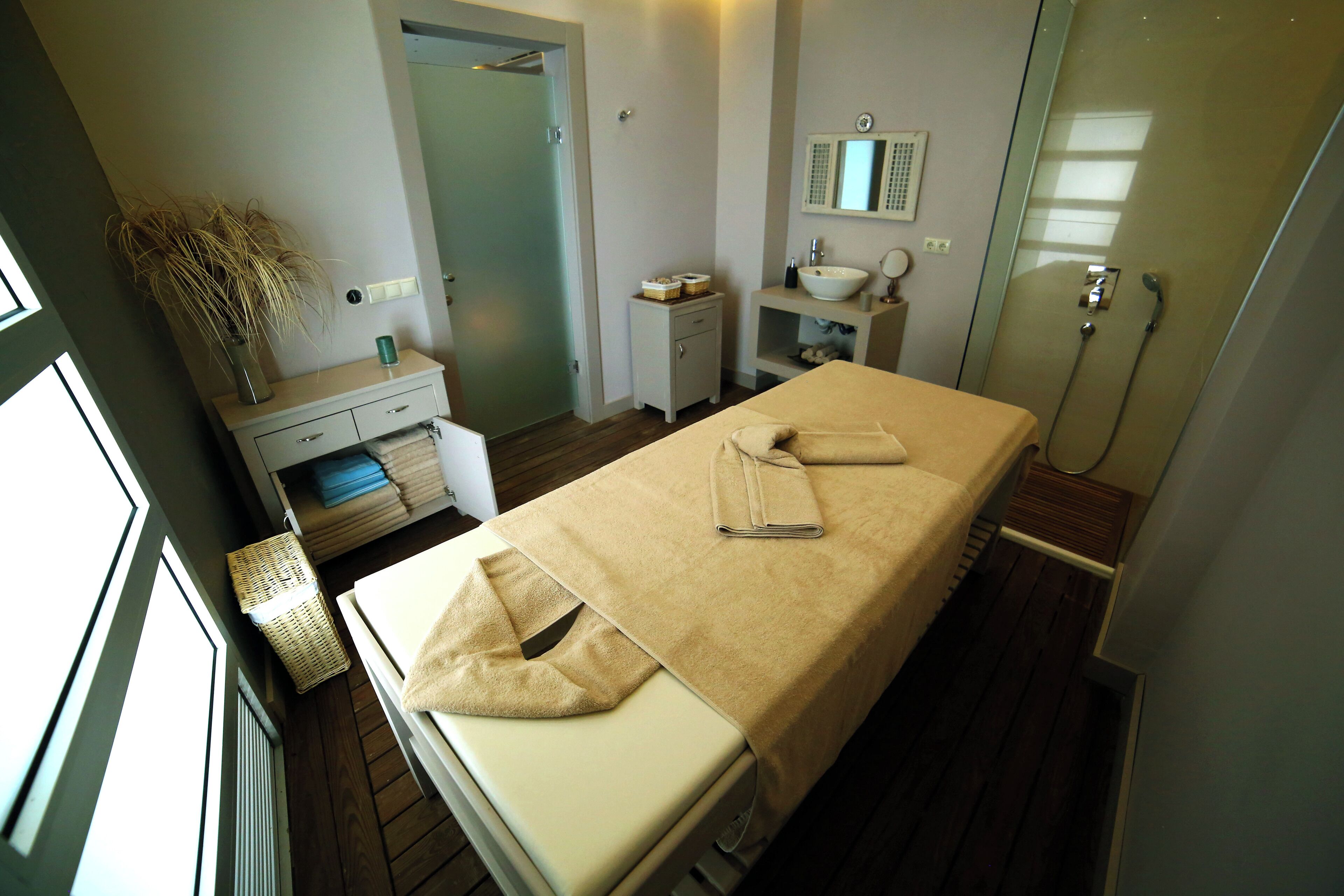 Una habitación de hotel con una cama, una mesita de noche pequeña, un espejo, un lavamanos y una ducha.