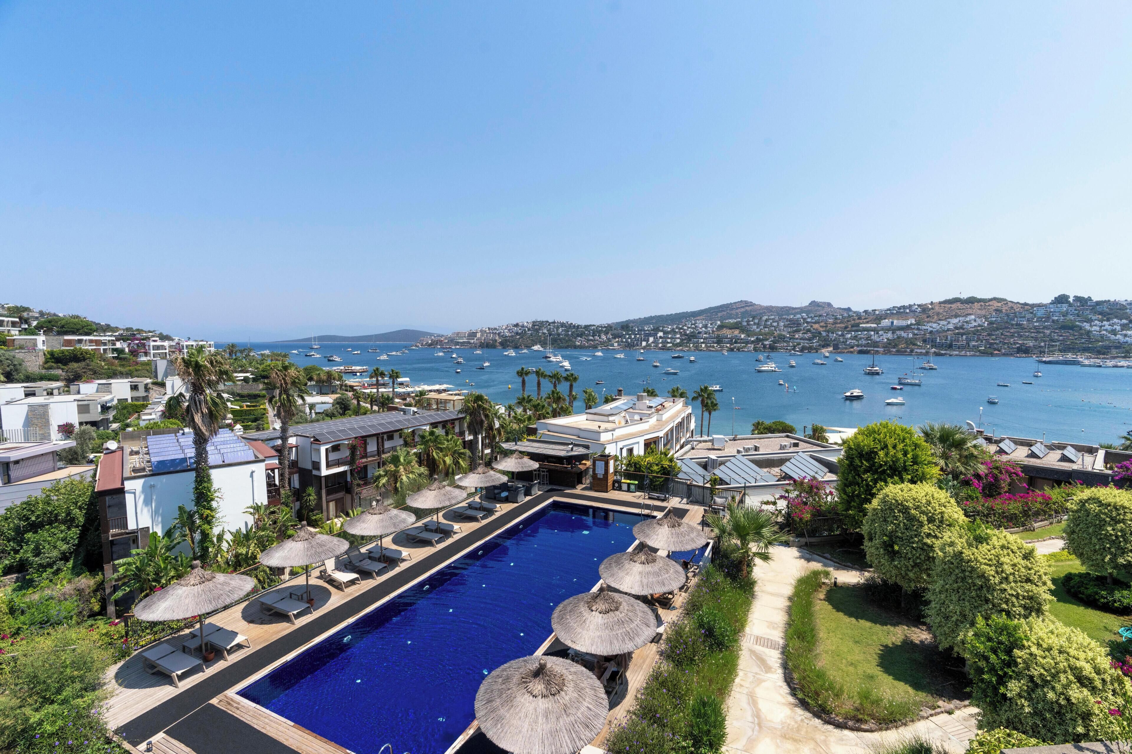 A resort with a swimming pool, sun loungers, and a view of the sea.
