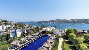 A resort with a swimming pool, sun loungers, and a view of the sea.