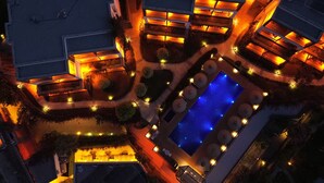 An aerial view of a resort with a central swimming pool, multiple lounge areas, and well-lit pathways. - Costa Farilya Special Class Hotel Bodrum - Special Class (Bodrum)