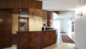 Un área de recepción con un mostrador de madera, un jarrón de flores y una lámpara roja.