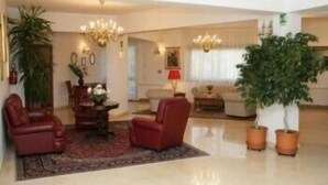 Un vestíbulo amplio con candelabro, zona de estar y plantas en macetas.