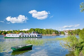 Un río con un bote verde y otro blanco, con gente a bordo.