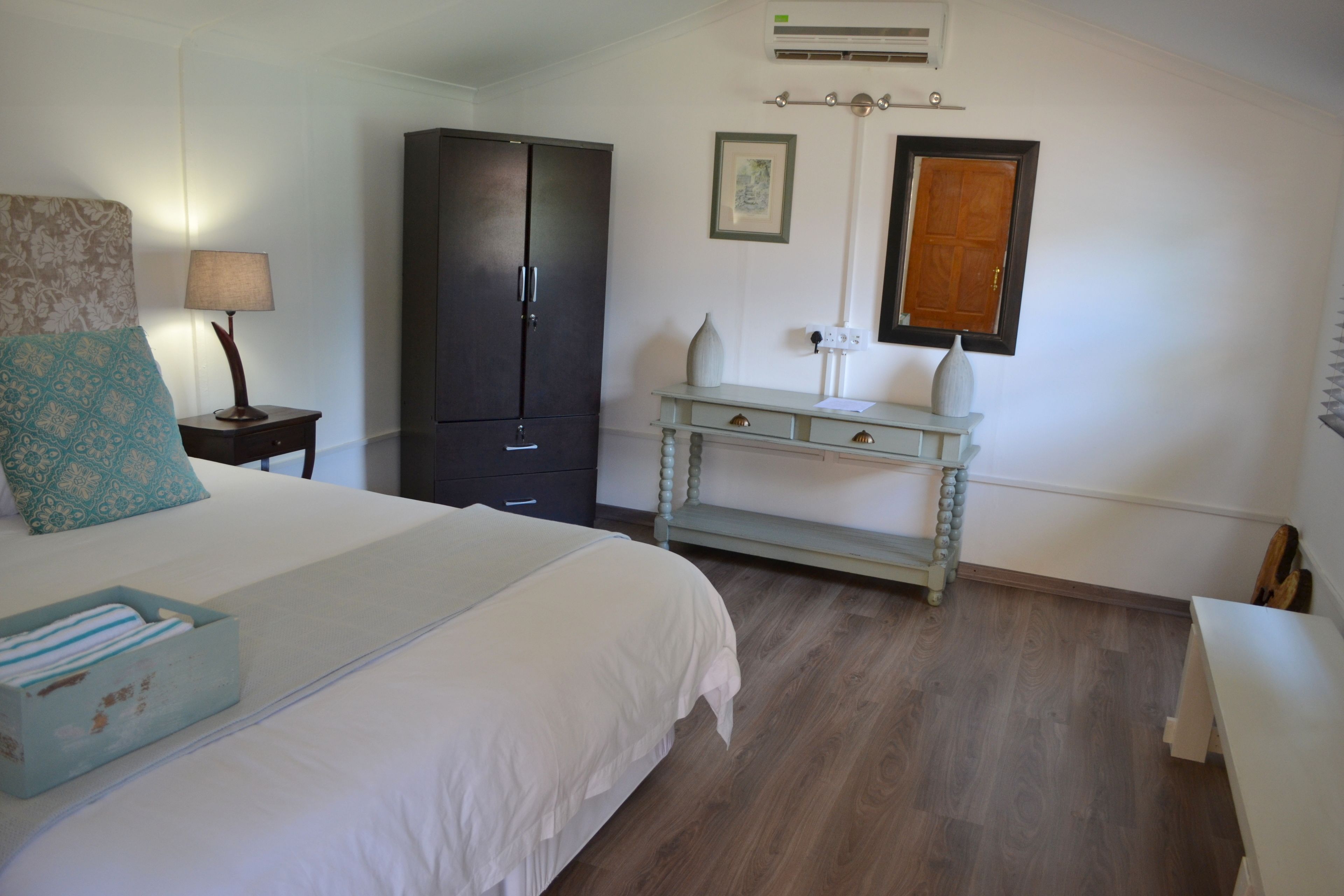 Une chambre à coucher comprenant un lit, une table de chevet, une commode, une coiffeuse et une fenêtre.