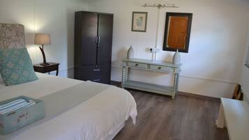 Une chambre à coucher comprenant un lit, une table de chevet, une commode, une coiffeuse et une fenêtre.