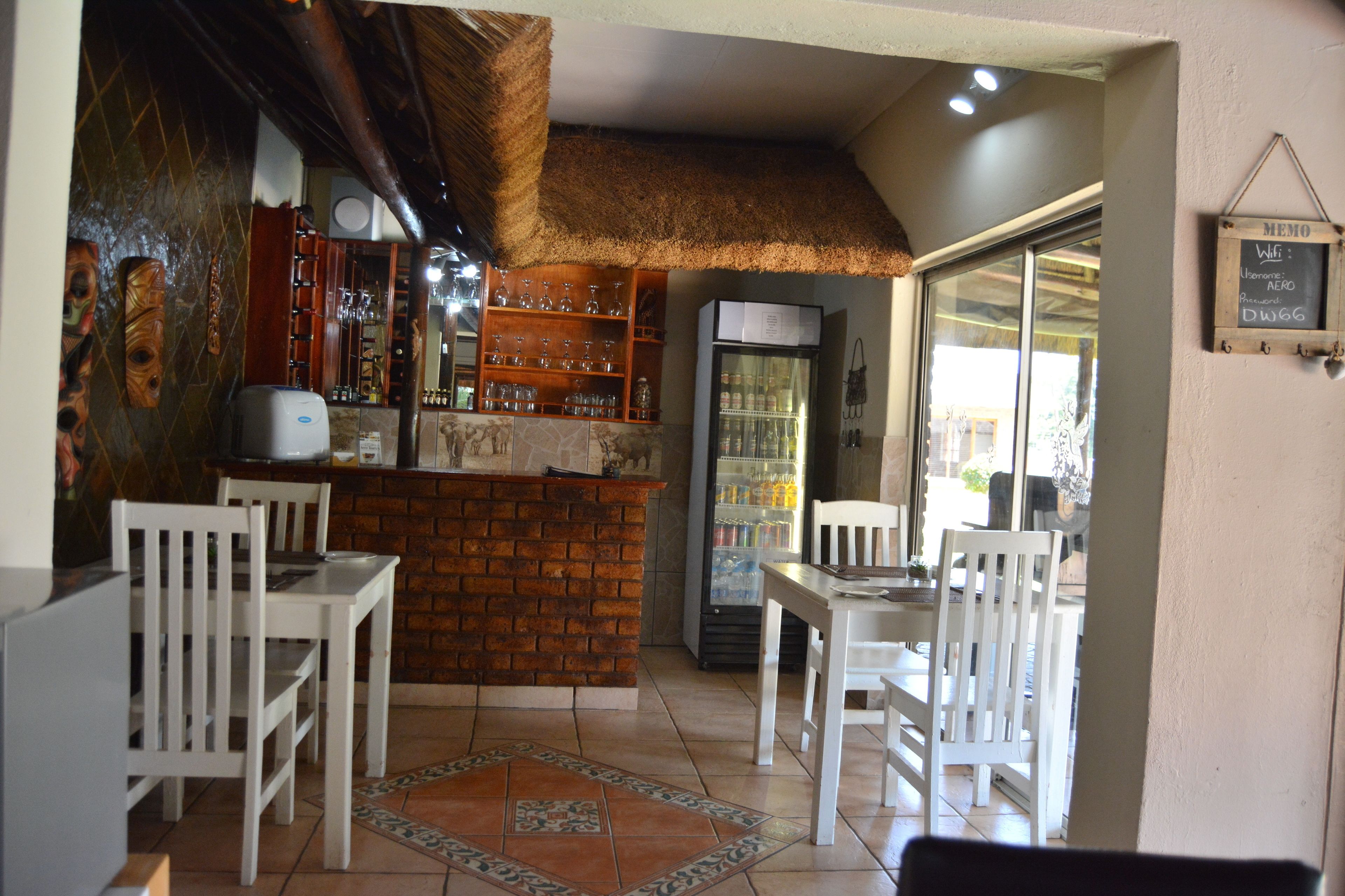 A restaurant with a brick counter, white chairs, and a refrigerator.