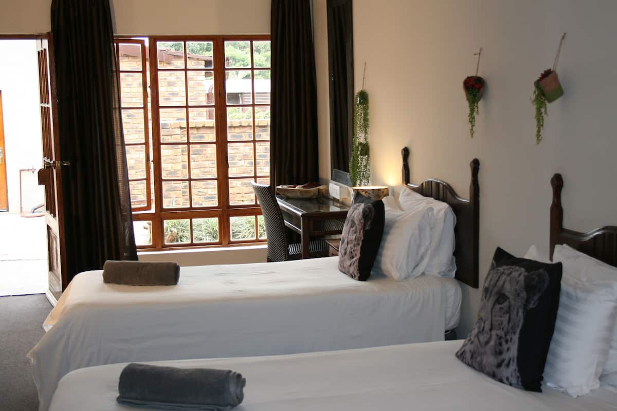 Ein Hotelzimmer mit zwei Betten, einem Schreibtisch und Blick nach draußen.