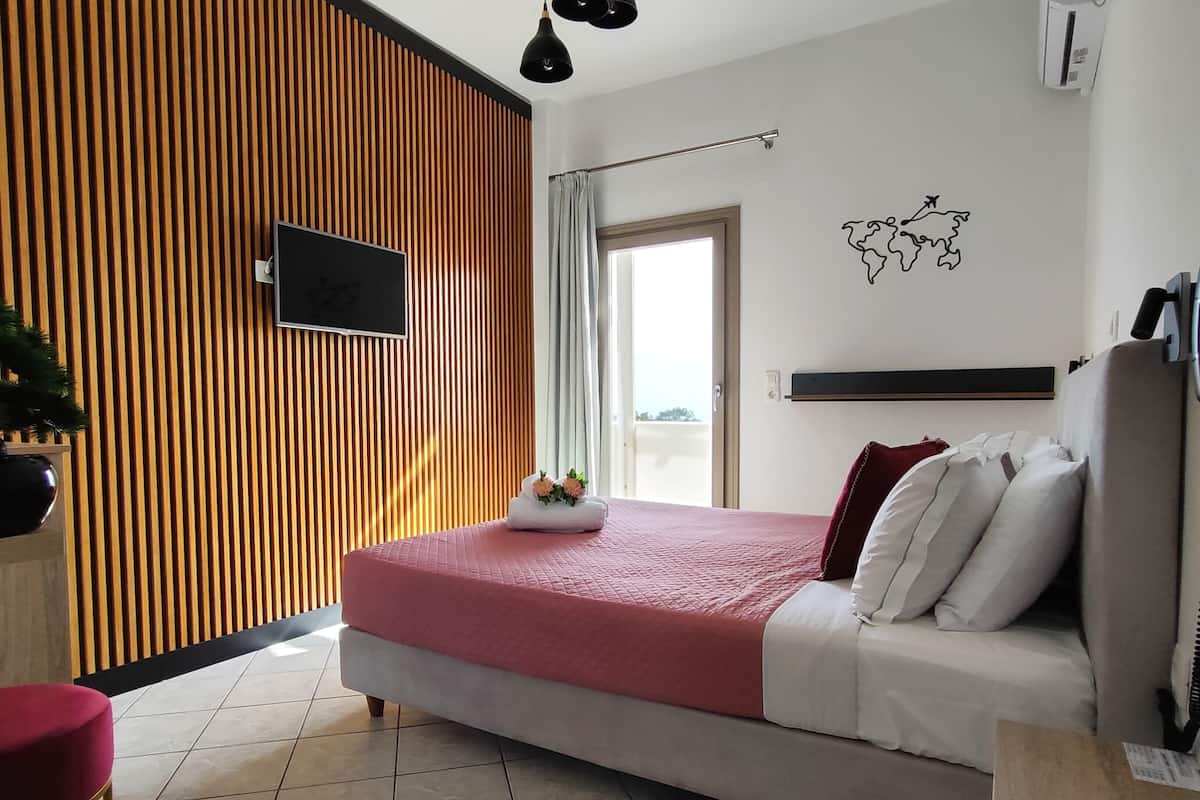 Une chambre moderne avec un lit, une télévision, un mur recouvert de lambris en bois, une fenêtre et un élément décoratif mural.