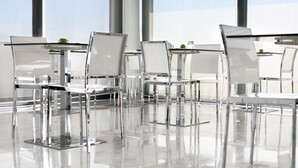 A modern, well-lit dining area with clear glass tables and chairs, reflecting the bright interior. - Benavente Vila Hotel (Benavente)