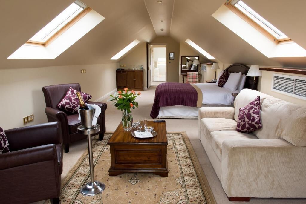 A spacious room with a high ceiling, a bed, a sofa, a chair, and a coffee table.