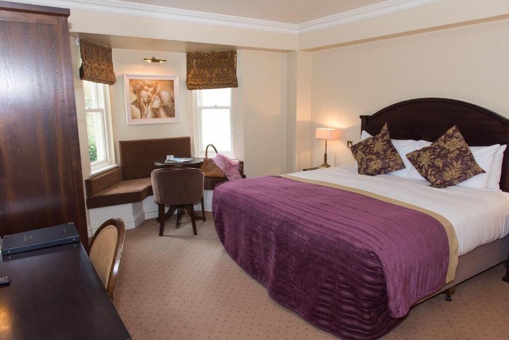 Une chambre d’hôtel avec un lit, un bureau, une chaise et une fenêtre.