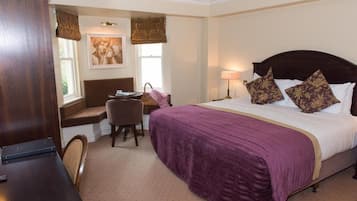 Une chambre d’hôtel avec un lit, un bureau, une chaise et une fenêtre.