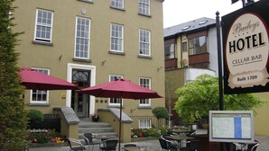 Un hôtel doté d’une terrasse et d’un bar situé dans une cave, dont la façade présente de nombreuses fenêtres et une enseigne indiquant qu’il a été construit en 1709.