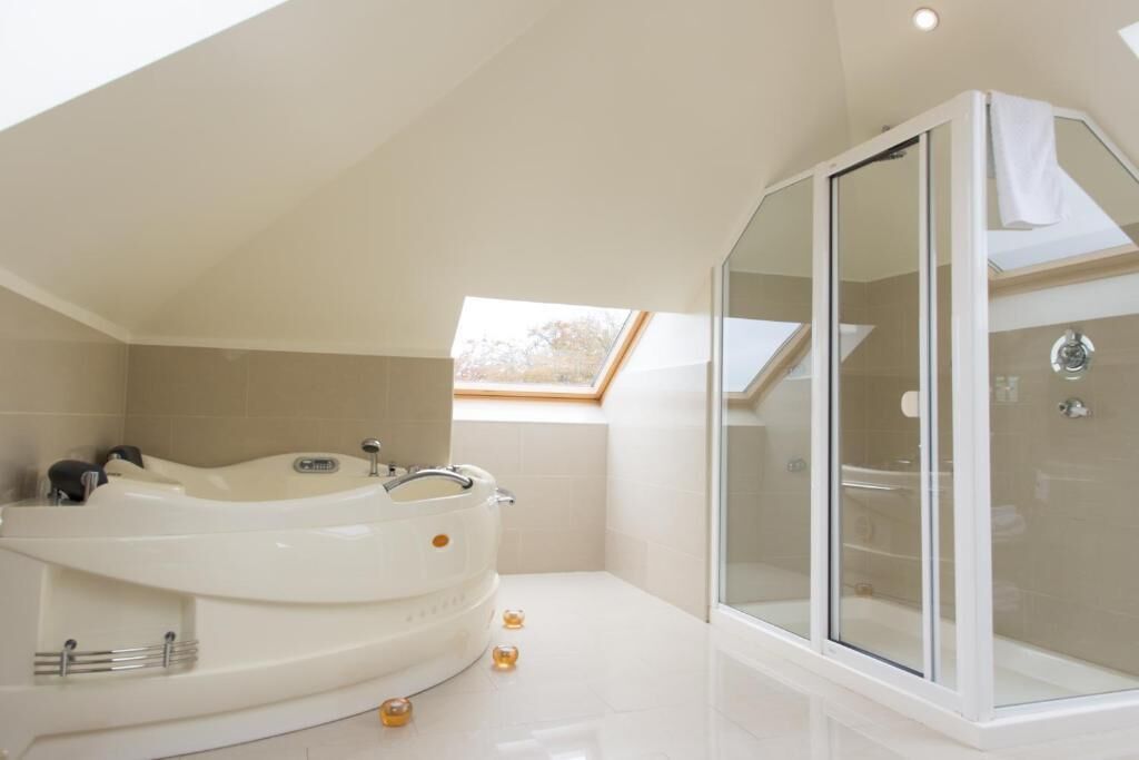 A modern bathroom with a freestanding bathtub, a glass-enclosed shower, and a skylight.