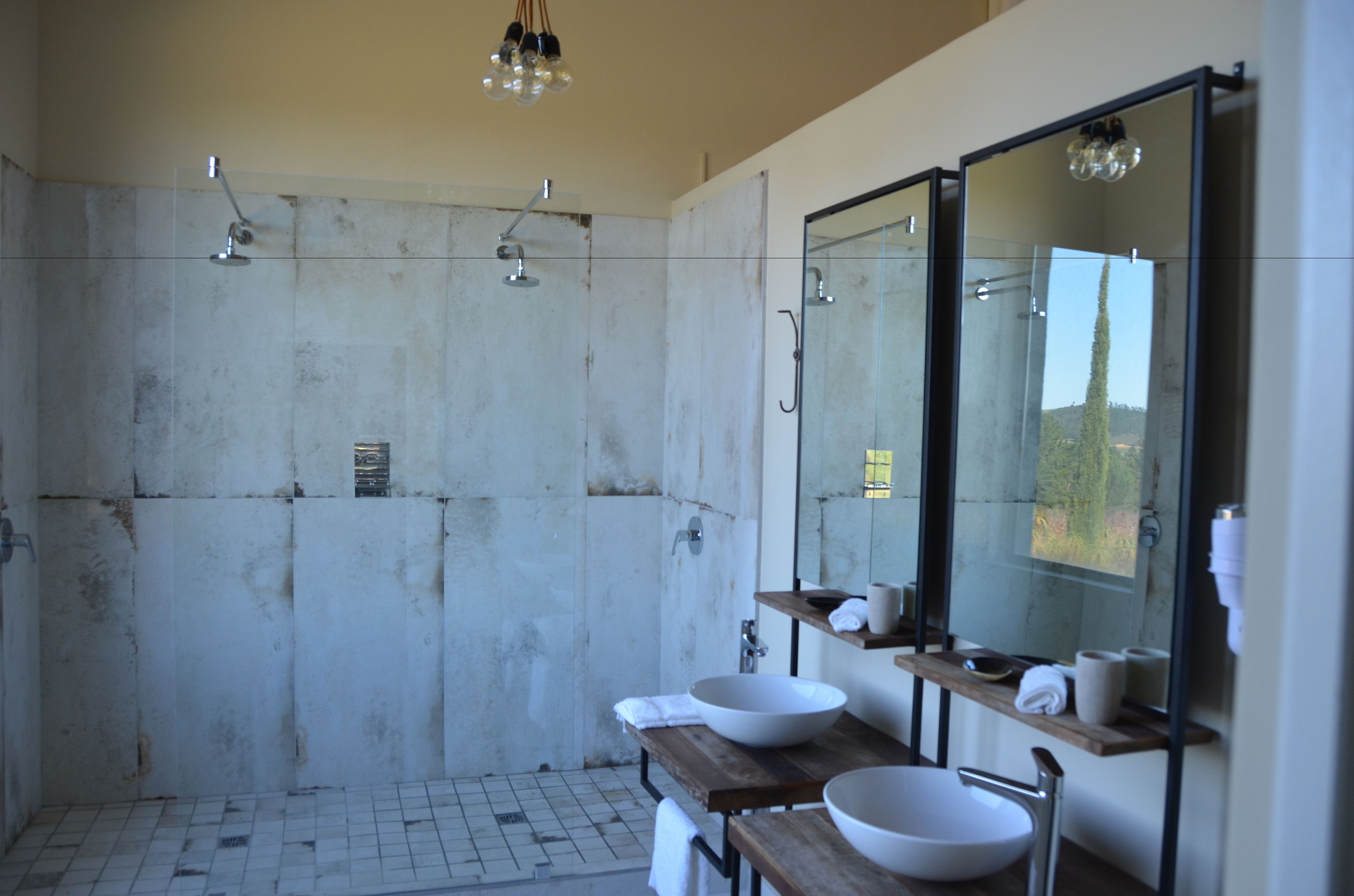 A modern bathroom with a large mirror, two sinks, and a shower area.