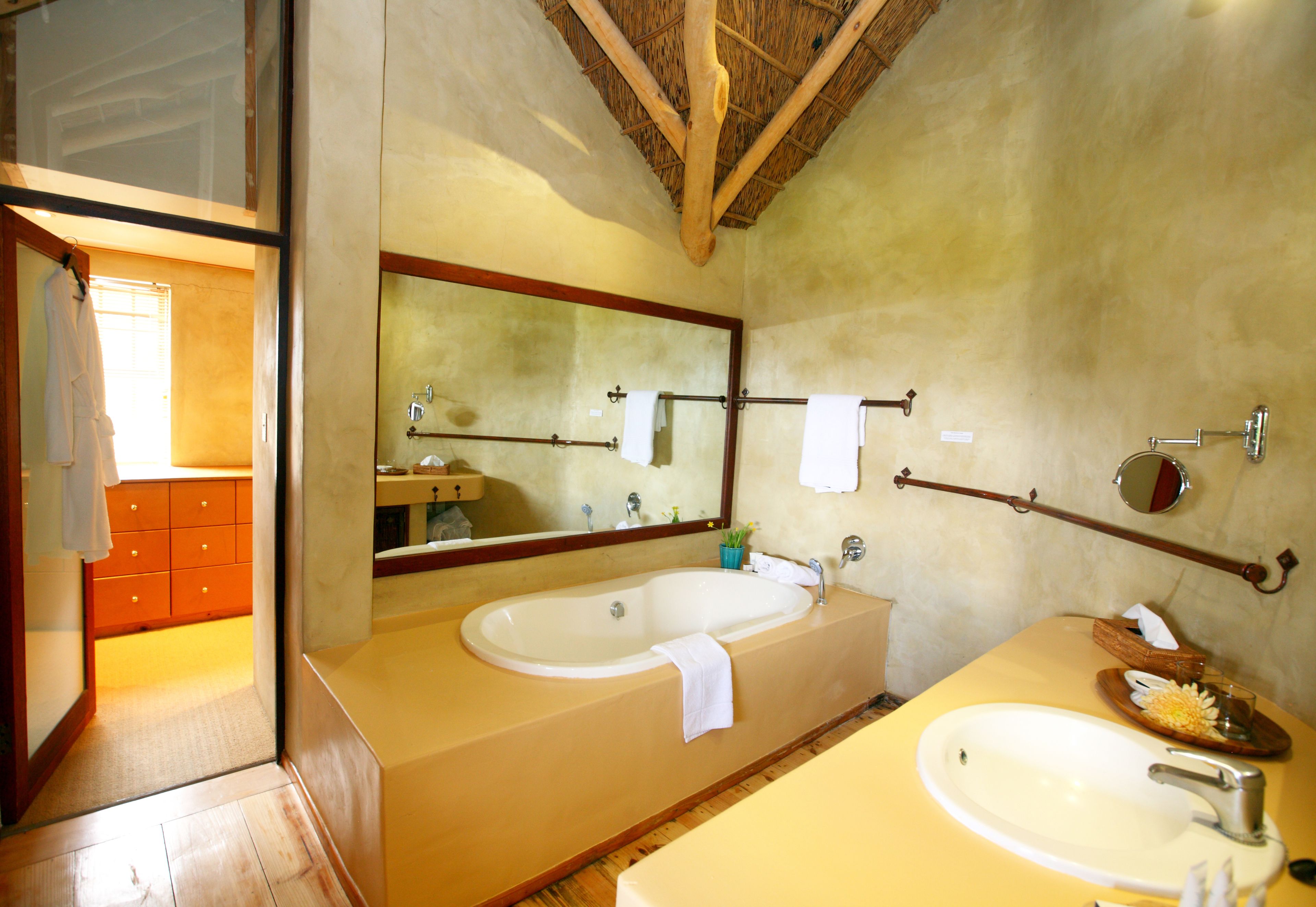 A bathroom with a wooden ceiling, two sinks, a large mirror, and a wooden vanity.