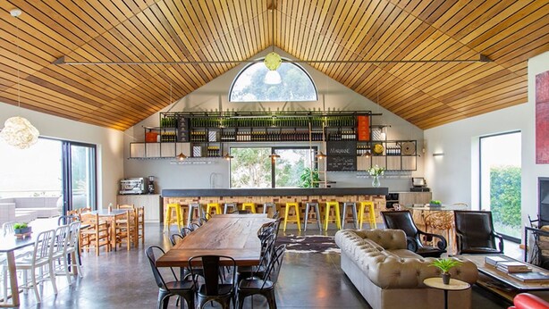 A spacious living area with a high ceiling, a large wooden dining table, and a cozy seating area. - Marianne Wine Estate (Stellenbosch)
