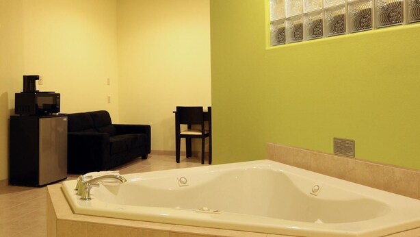 Un bagno moderno con una vasca freestanding, una macchina per caffè e un’area salotto con una poltrona e un divano.