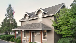 A two-story building with a porch, a flagpole with an American flag, and a sign that reads "Visitor Information." - Wine Country Inn (Jacksonville)