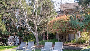 A garden with wooden chairs, a pergola, and a house in the background. - Wine Country Inn (Jacksonville)