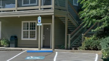 Un edificio con zona de estacionamiento adaptado para personas con discapacidad, una escalera y una puerta que indica "RESERVED PARKING".