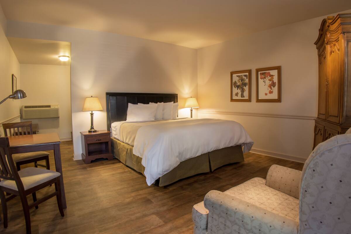 Ein Hotelzimmer mit Bett, Nachttischen, einem Schreibtisch, einem Stuhl und einem Kleiderschrank.