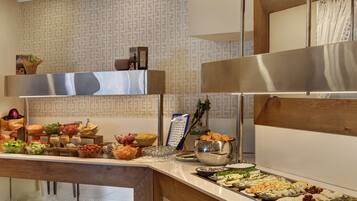 A buffet with various food items and a large stainless steel appliance.