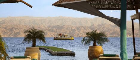 A wooden deck with lounge chairs and a boat in the background.