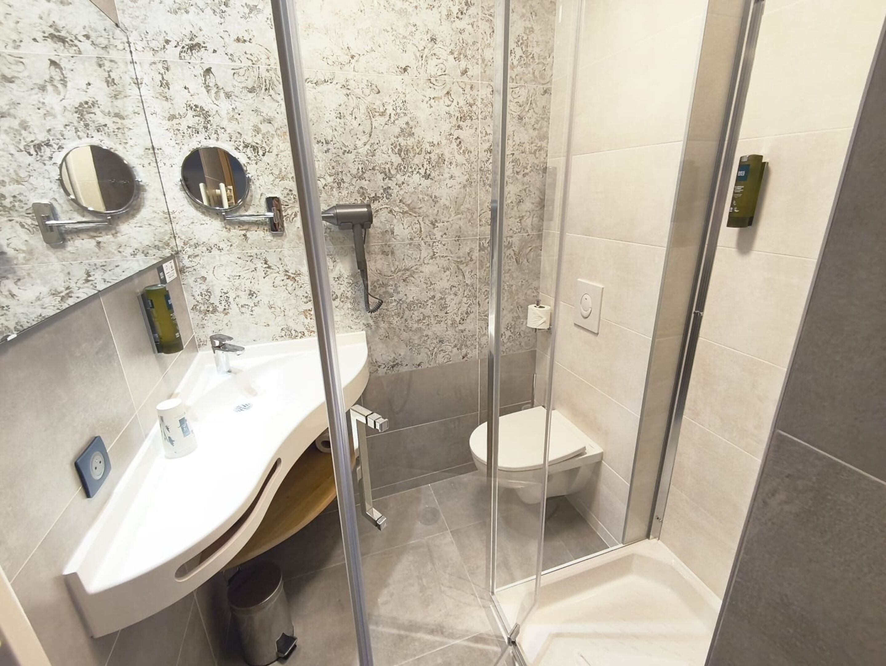 Ein modernes Badezimmer mit einer Duschkabine, einem weißen Waschbecken und einer Toilette.