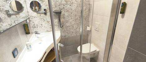 A modern bathroom with a glass-enclosed shower, a white sink, and a toilet.