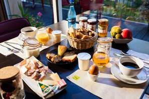 A breakfast table with various food items, including bread, cheese, eggs, and fruits.